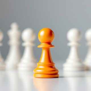 Ein orangefarbener Spielstein hebt sich von weissen Figuren ab als Symbol fuer das Alleinstellungsmerkmal