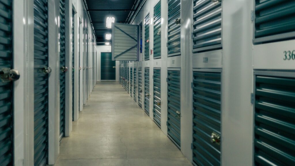 Heller Gang einer modernen Selfstorage-Anlage mit nummerierten Lagerabteilen und verschlossenen Rolltoren