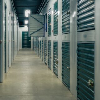 Heller Gang einer modernen Selfstorage-Anlage mit nummerierten Lagerabteilen und verschlossenen Rolltoren